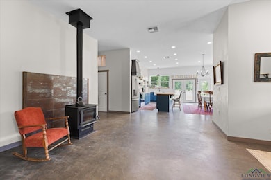 Living room featuring a wood stove, concrete flooring, recessed lighting, french doors, and a chandelier