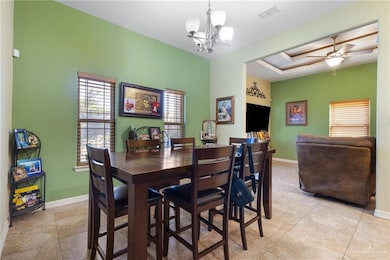 Dining space featuring healthy amount of natural light, a chandelier, light tile patterned floors, and ceiling fan