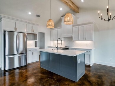 Kitchen featuring white cabinets, hanging light fixtures, and stainless steel refrigerator