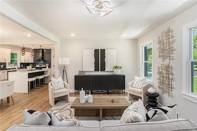 Living area with light wood finished floors and recessed lighting
