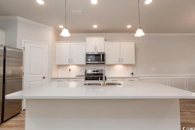 Kitchen with pendant lighting, white cabinets, a c
