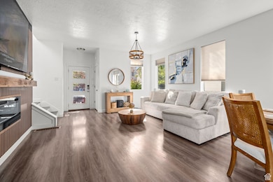 Living area with a textured ceiling, dark wood finished floors, a fireplace, stairs, and a chandelier
