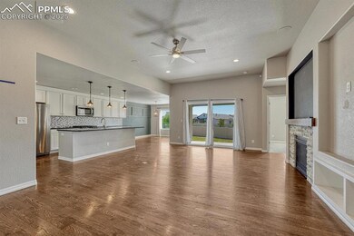 Step into the family room, where a ceiling fan, stone fireplace, and stunning wood floors converge to create a warm and inviting atmosphere, complete with a textured ceiling, walkout to the covered patio, and recessed lighting.
