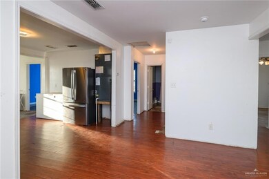 Unfurnished living room featuring attic access, visible vents, and wood finished floors