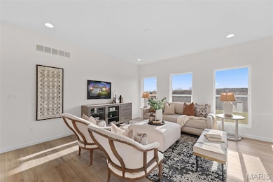 Living room with light wood finished floors and recessed lighting