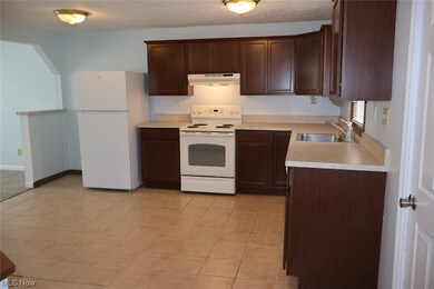 Kitchen with white appliances, light tile flooring, sink, and dark brown cabinetry