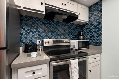 Kitchen with appliances with stainless steel finishes, exhaust hood, decorative backsplash, white cabinets, and light countertops