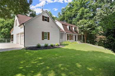 Back of house featuring roof with shingles, a chimney, concrete driveway, a yard, and an attached garage