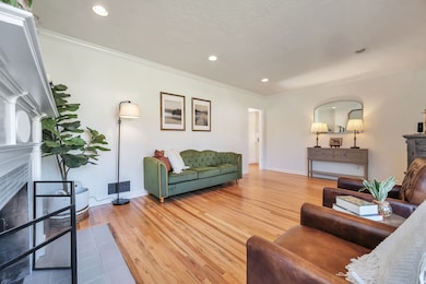 Living area featuring a tiled fireplace, wood finished floors, ornamental molding, and recessed lighting