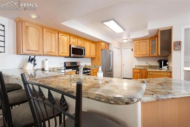 Kitchen featuring stainless steel appliances, light stone countertops, glass insert cabinets, a breakfast bar area, and a peninsula