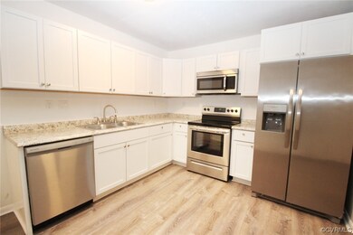 Kitchen with light hardwood / wood-style floors, white cabinets, sink, and appliances with stainless steel finishes