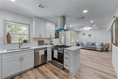 Kitchen with stainless steel appliances, island exhaust hood, a sink, a peninsula, and tasteful backsplash