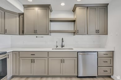 Kitchen with gray cabinetry, appliances with stainless steel finishes, recessed lighting, open shelves, and light stone counters