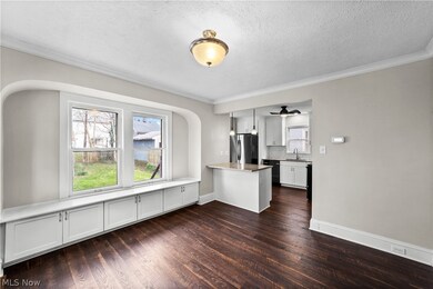 Dining with dark LVT wood-style flooring, crown molding, sink, and a textured ceiling