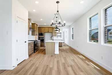 Kitchen featuring stainless steel appliances, wall chimney range hood, recessed lighting, brown cabinets, and light countertops