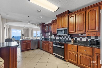 Kitchen featuring tasteful backsplash, dark stone counters, light tile patterned floors, stainless steel appliances, and a textured ceiling