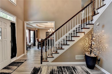 Foyer with a towering ceiling, baseboards, stairs,