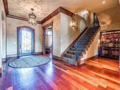 Foyer with a chandelier, wood-type flooring, stairs, ornamental molding, and baseboards