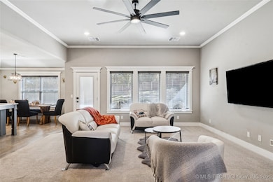 Spacious living room featuring soft carpeting, crown molding, recessed lighting, and a modern black ceiling fan. Large windows bring in beautiful natural light and enhance the open-concept flow into the kitchen.