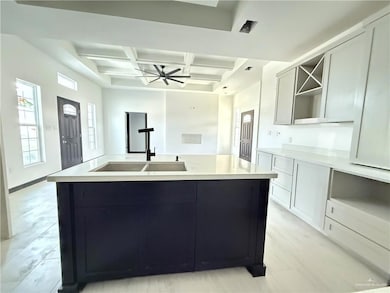Kitchen with coffered ceiling, a sink, a kitchen island with sink, beam ceiling, and open shelves