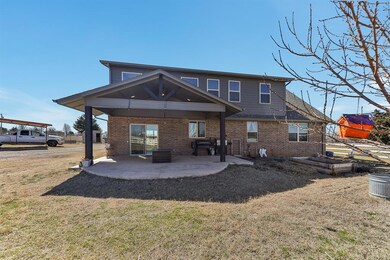 Back of house with brick siding, a yard, and a pat