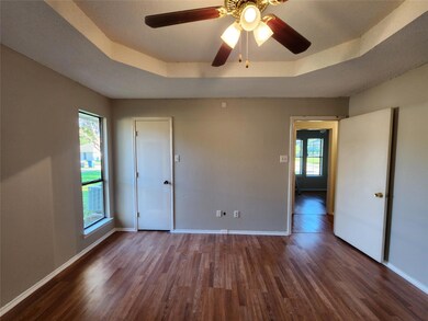 Unfurnished bedroom featuring hardwood / wood-style flooring, a raised ceiling, and multiple windows