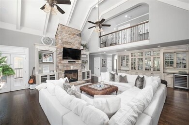 Living area with high vaulted ceiling, beverage cooler, beam ceiling, dark wood-type flooring, and a fireplace