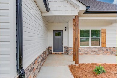 View of exterior entry with a porch, roof with shingles, and stone siding