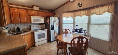 Kitchen with white appliances, wallpapered walls, vaulted ceiling, crown molding, and a sink