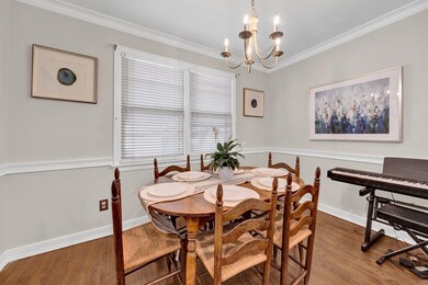 Dining space with a chandelier, wood finished floors, crown molding, and baseboards