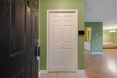Tiled entryway with a notable chandelier