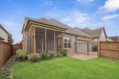 Rear view of property with brick siding, a fenced backyard, an attached garage, and a sunroom