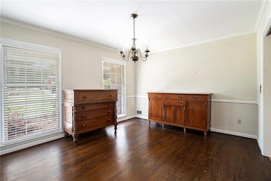 Dining space with a chandelier, baseboards, dark wood-style floors, and crown molding