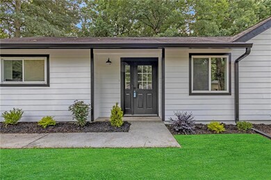 Property entrance with a lawn and roof with shingles