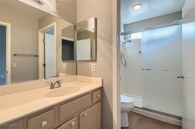 Bathroom featuring a stall shower, vanity, tile pa