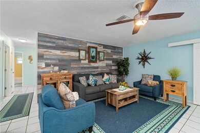 Living area with tile patterned floors, an accent wall, wooden walls, a textured ceiling, and ceiling fan