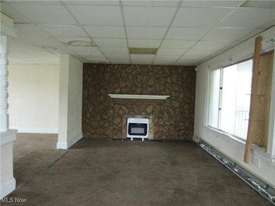 Unfurnished living room with heating unit, a fireplace, a paneled ceiling, and carpet flooring