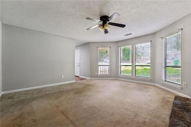 Empty room featuring carpet, ceiling fan, baseboar