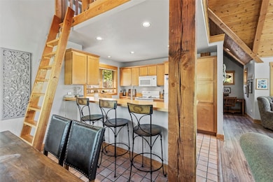 Kitchen with white appliances, a kitchen bar, ligh