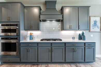 The cooktop measures 36-inches wide, and rests under this wood hood vent. Photo of model home, colors and options vary. *Photo of model home, colors and options vary.