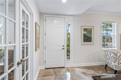 Tiled foyer entrance with crown molding and french