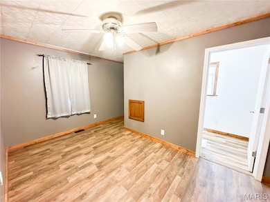 Empty room with crown molding, light wood-style flooring, and ceiling fan