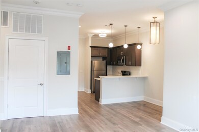 Kitchen with dark brown cabinetry, ornamental molding, pendant lighting, a peninsula, and appliances with stainless steel finishes