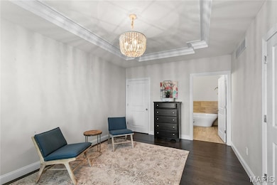 Living area with a tray ceiling, dark wood-type flooring, and a chandelier