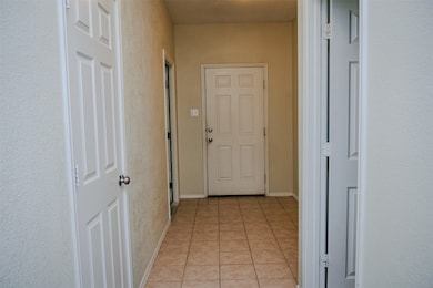 Hall with light tile patterned floors and baseboards