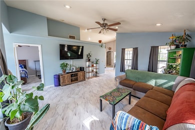 Living area featuring ceiling fan, vaulted ceiling