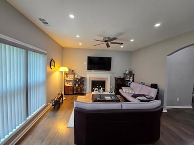 Living room featuring arched walkways, a ceiling fan, dark wood-style flooring, recessed lighting, and a fireplace
