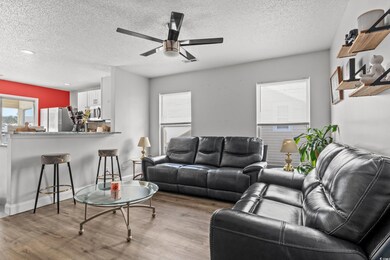 Living room with ceiling fan, a textured ceiling, and light hardwood / wood-style floors