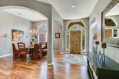 Foyer entrance with arched walkways, light wood-type flooring, baseboards, a chandelier, and recessed lighting