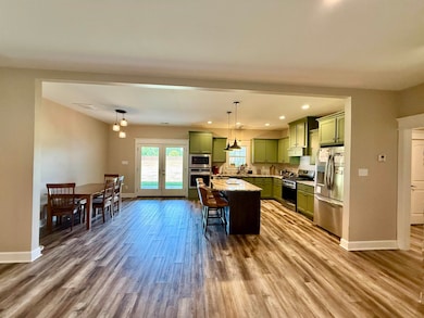 Kitchen featuring green cabinets, appliances with stainless steel finishes, recessed lighting, a kitchen bar, and a center island